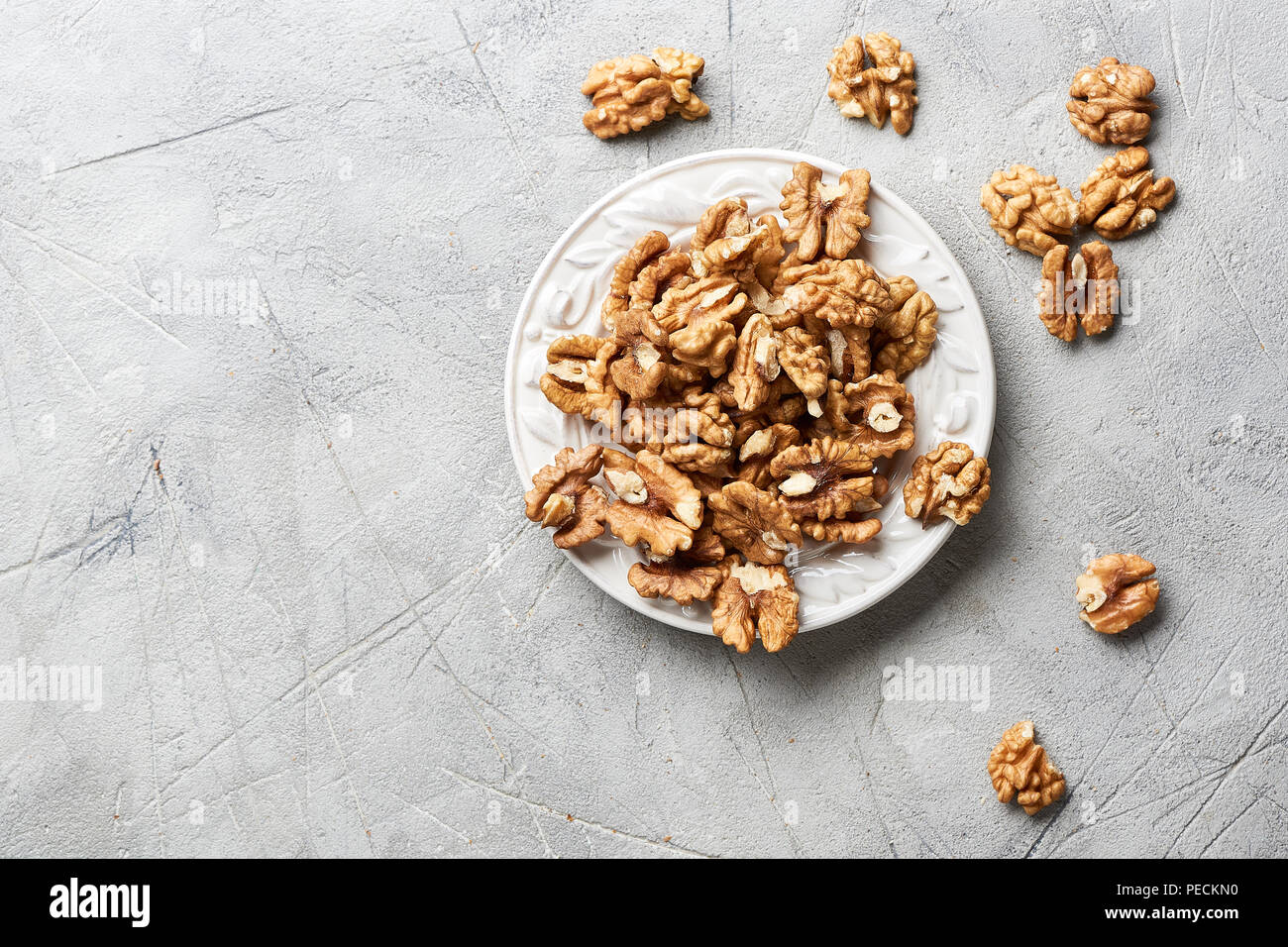 Walnut kernels on white plate over gray background. Stock Photo