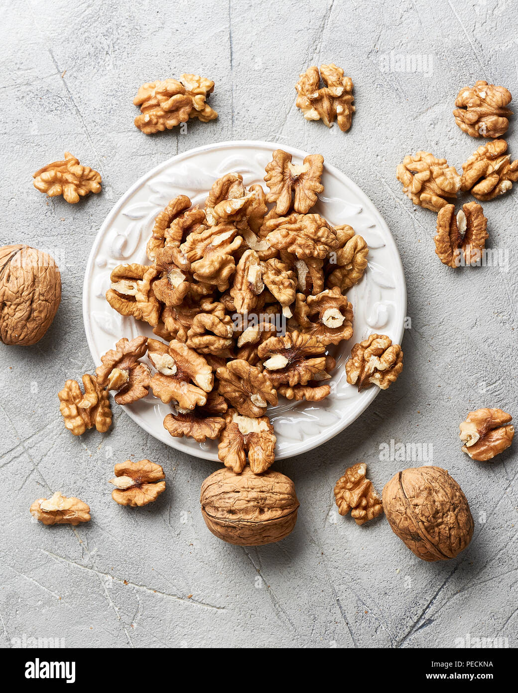 Walnut kernels on white plate over gray background. Stock Photo