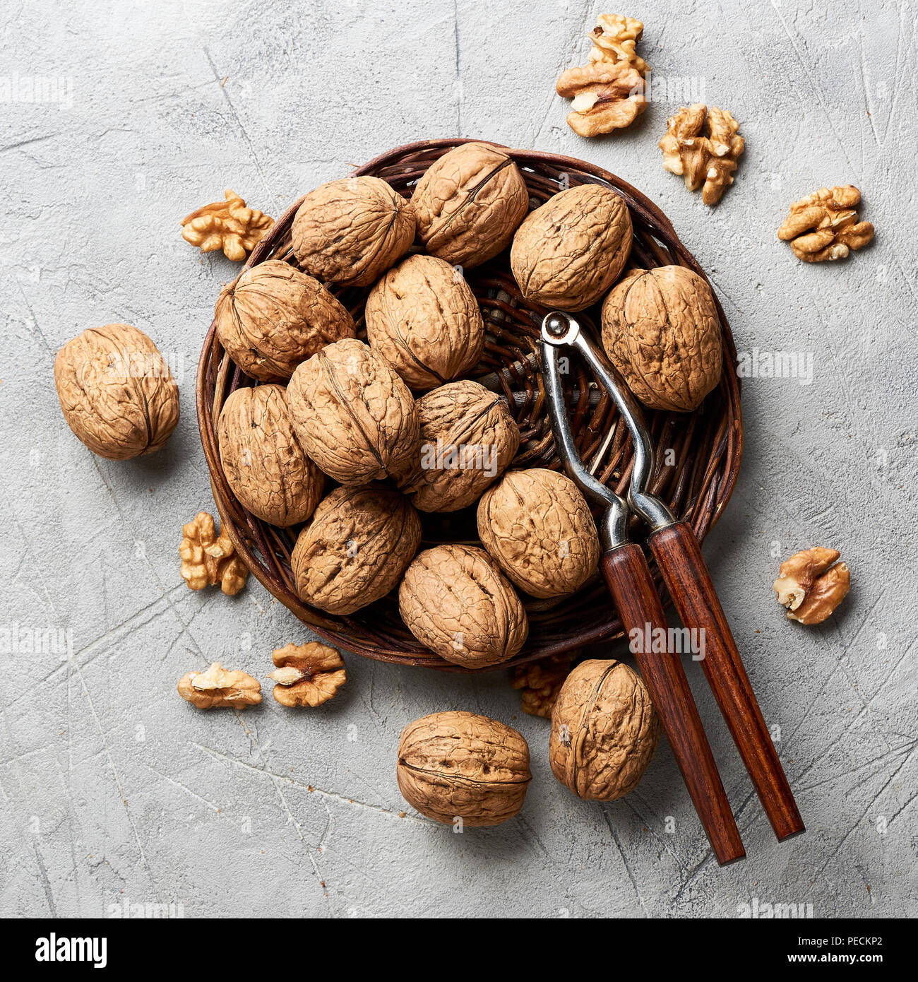 Whole walnuts and kernels on gray background and nutcracker. Stock Photo