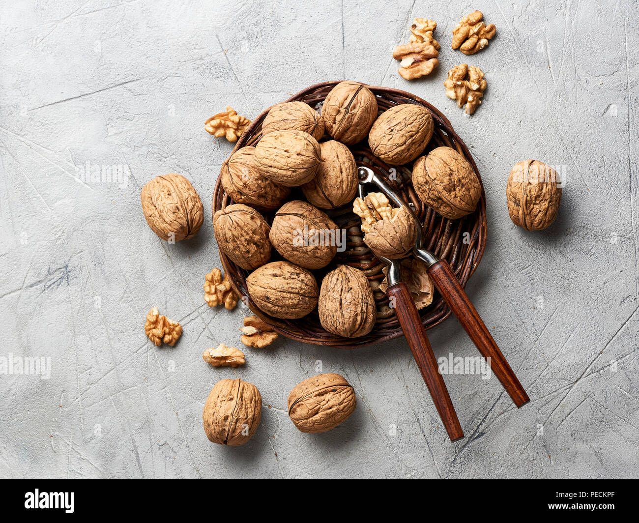 Whole walnuts and kernels on gray background and nutcracker. Stock Photo