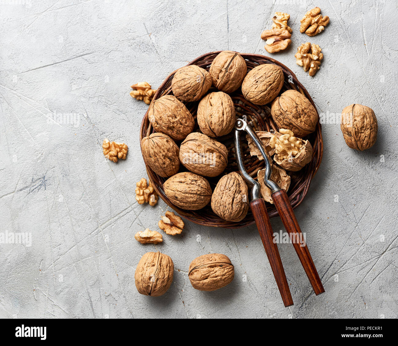 Whole walnuts and kernels on gray background and nutcracker. Stock Photo