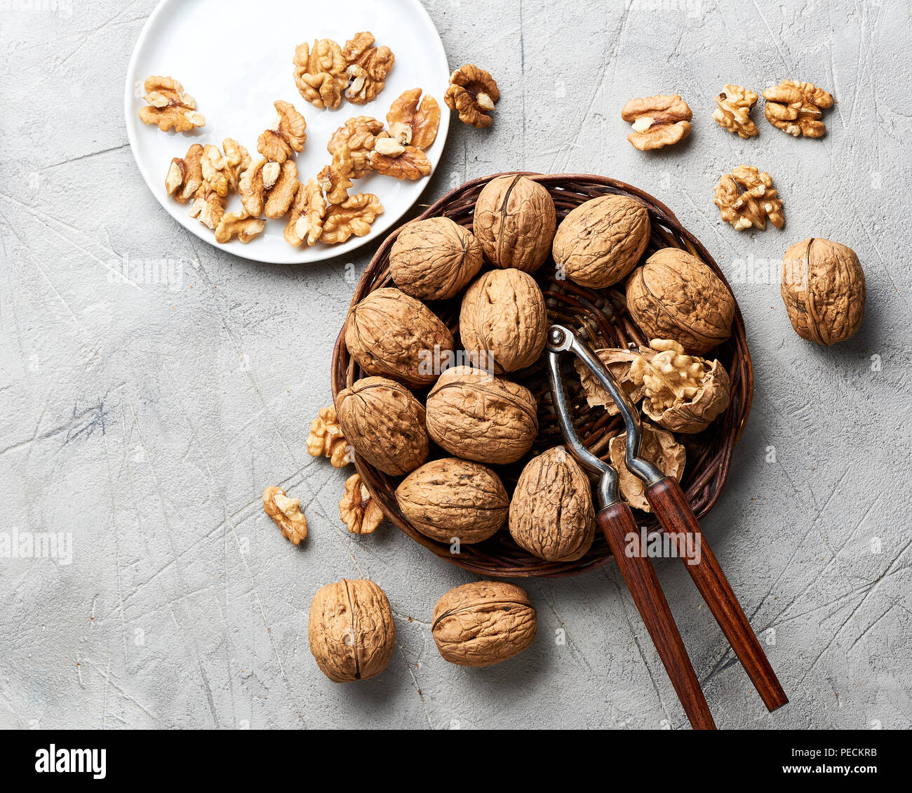 Whole walnuts and kernels on gray background and nutcracker. Stock Photo