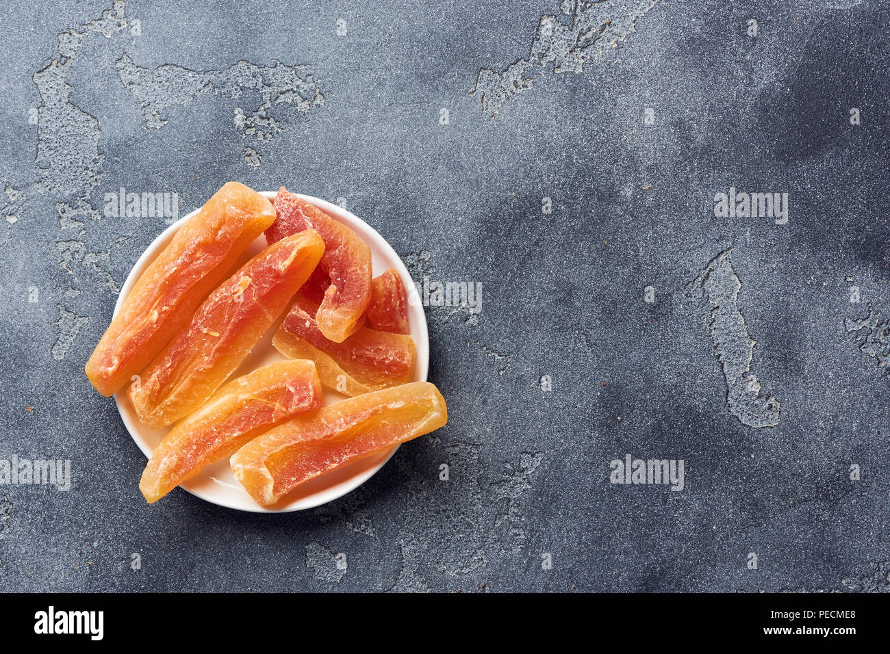 Dried sweet papaya sticks. Candied fruits on gray background. Top view