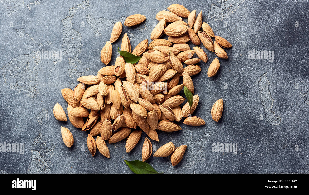 Unshelled almonds on gray concrete background with copy space. Top view. Stock Photo
