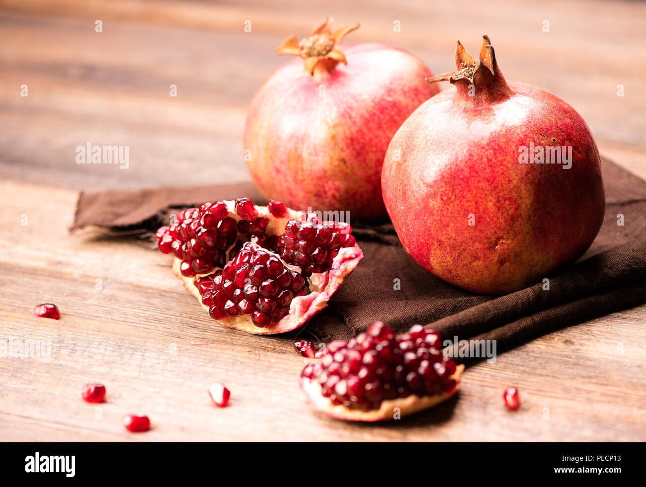 Pomegranate fruits with grains on wooden table. Stock Photo