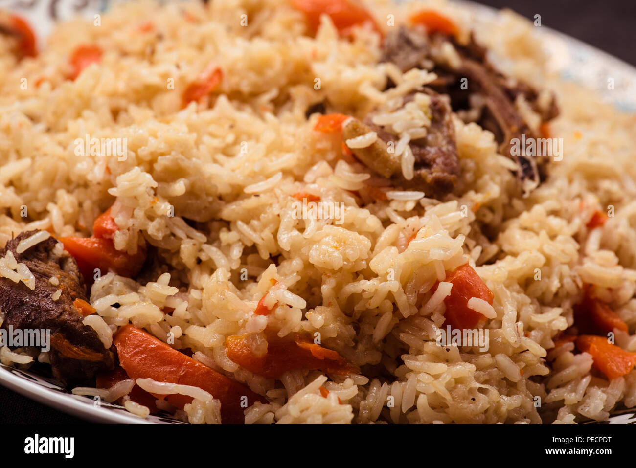 Pilaf on plate with oriental ornament. Central-Asian cuisine - Plov. Macro. Stock Photo