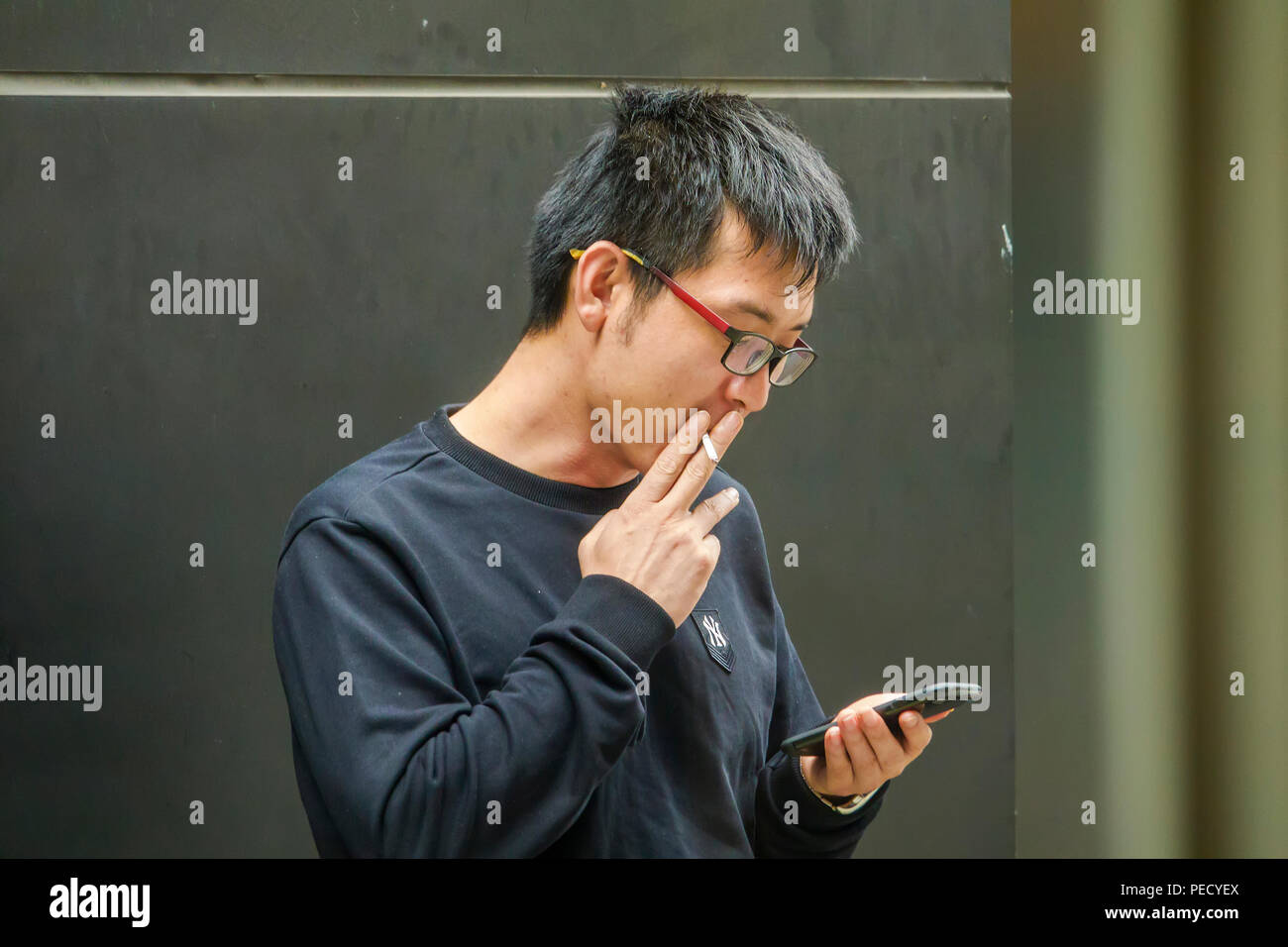 South Korean man smoking while using phone Busan Pusan Korea Asia Stock