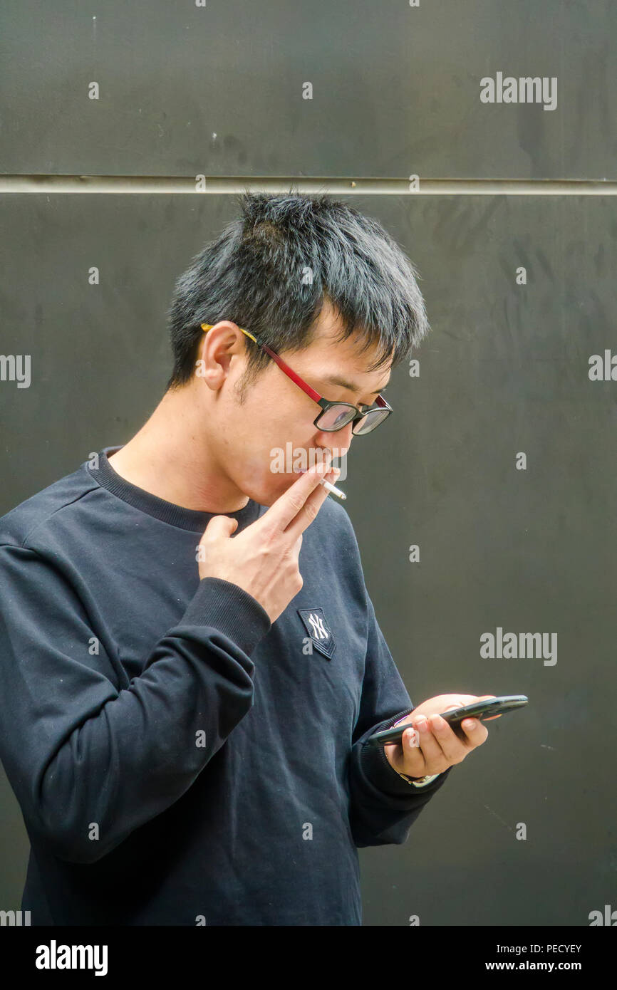 South Korean man smoking while using phone Busan Pusan Korea Asia Stock