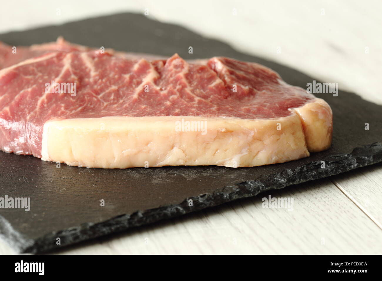 Sirloin steak beef joints on a slate cutting board on a grey wood