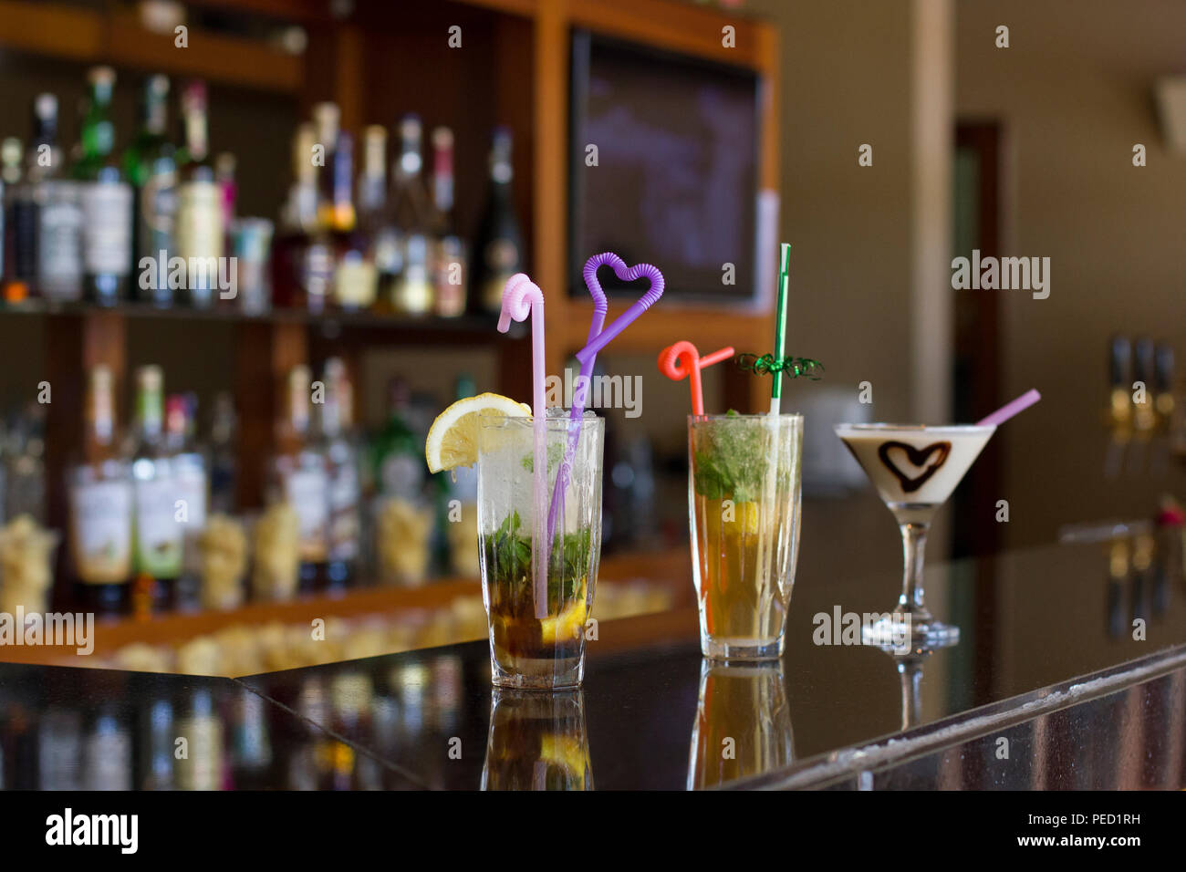 Three cocktails on the bar - Mojito with ice and straw, Pina Colada with a chocolate heart Stock Photo