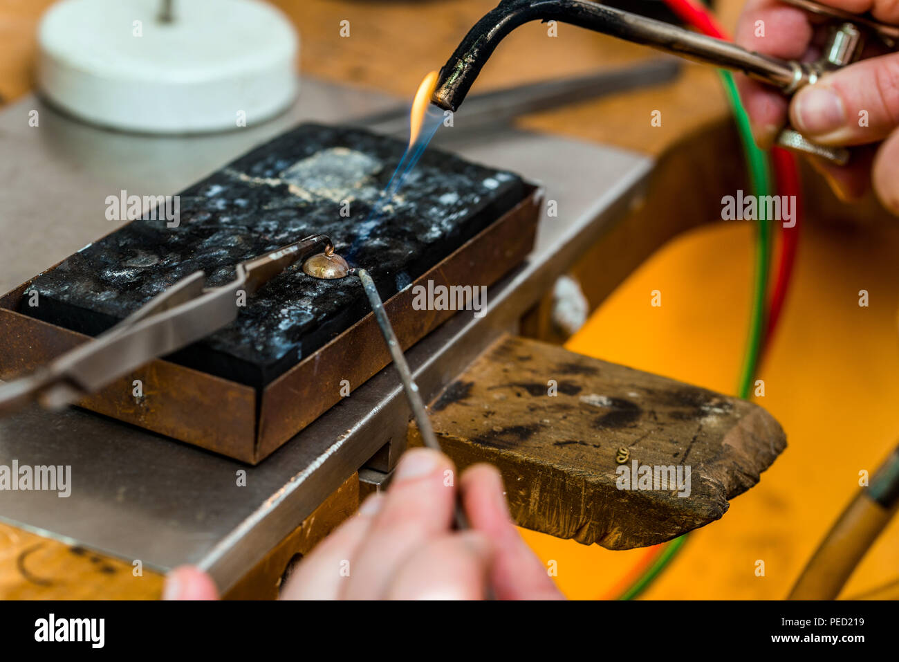 Goldsmith working and soldering an unfinished jewelry piece with a