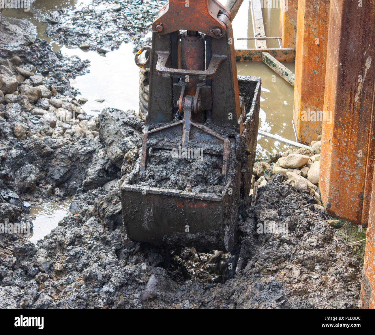 mechanical digger with bucket excavating a trench on a building site. Stock Photo