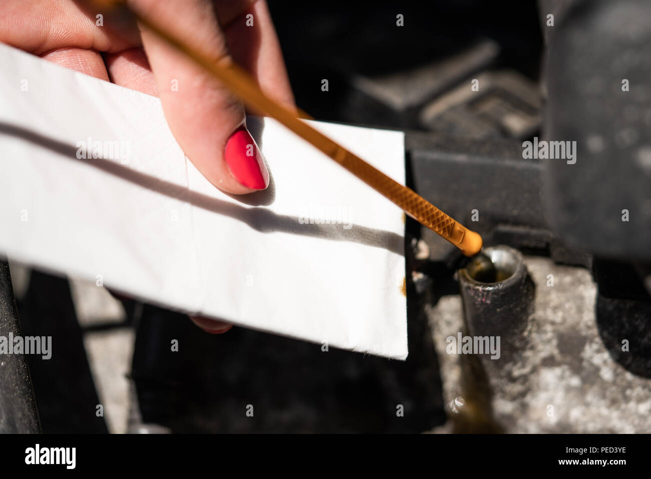 A woman is checking the oil level gauge. Stock Photo