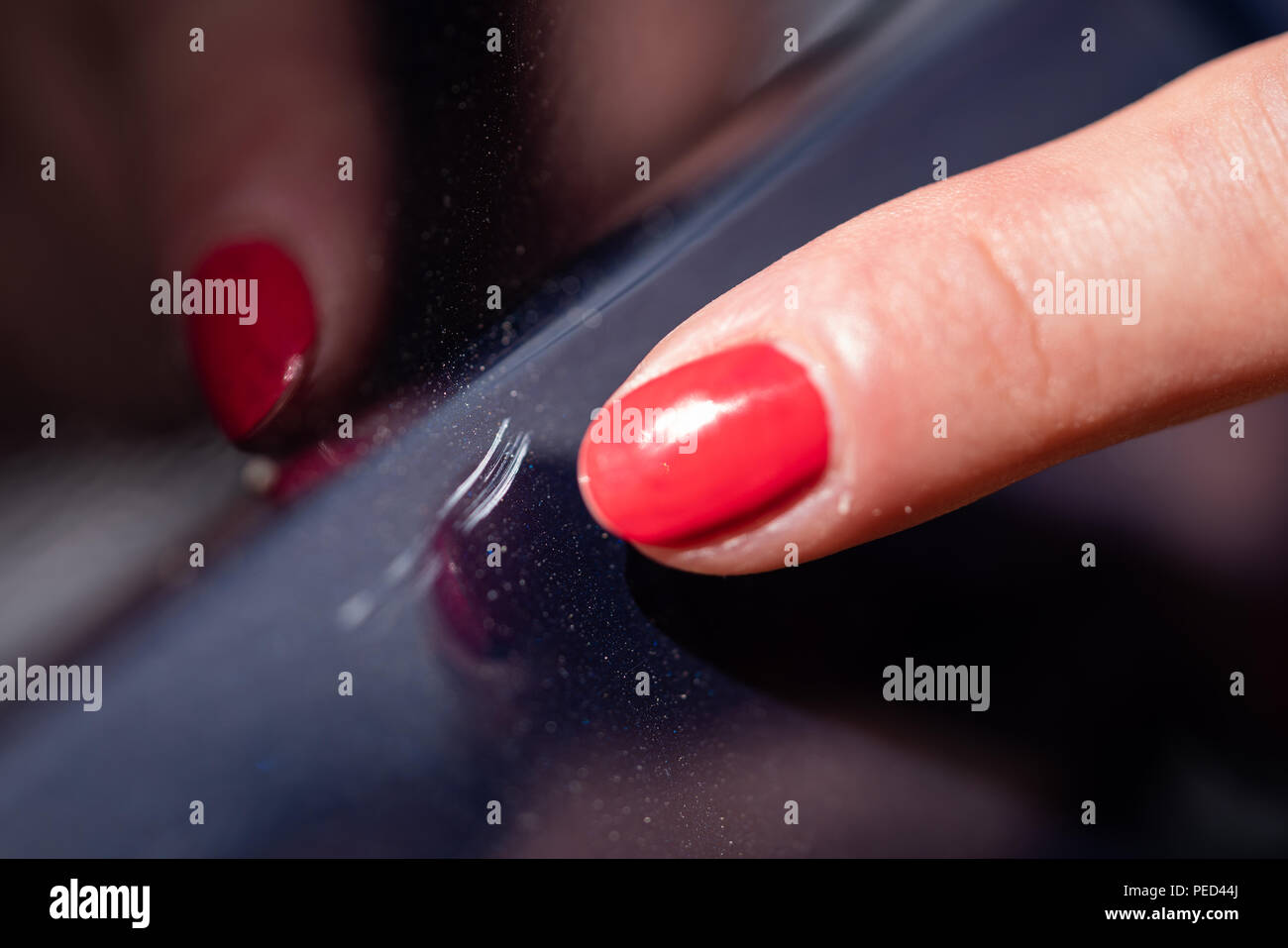 A woman shows scratches in a car paint. Stock Photo