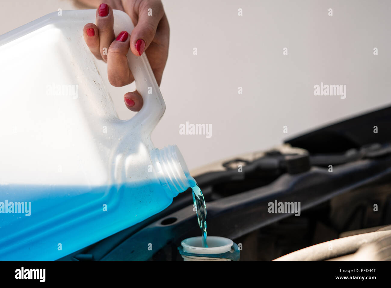 A woman is filling the water for the windshield washer system. Stock Photo