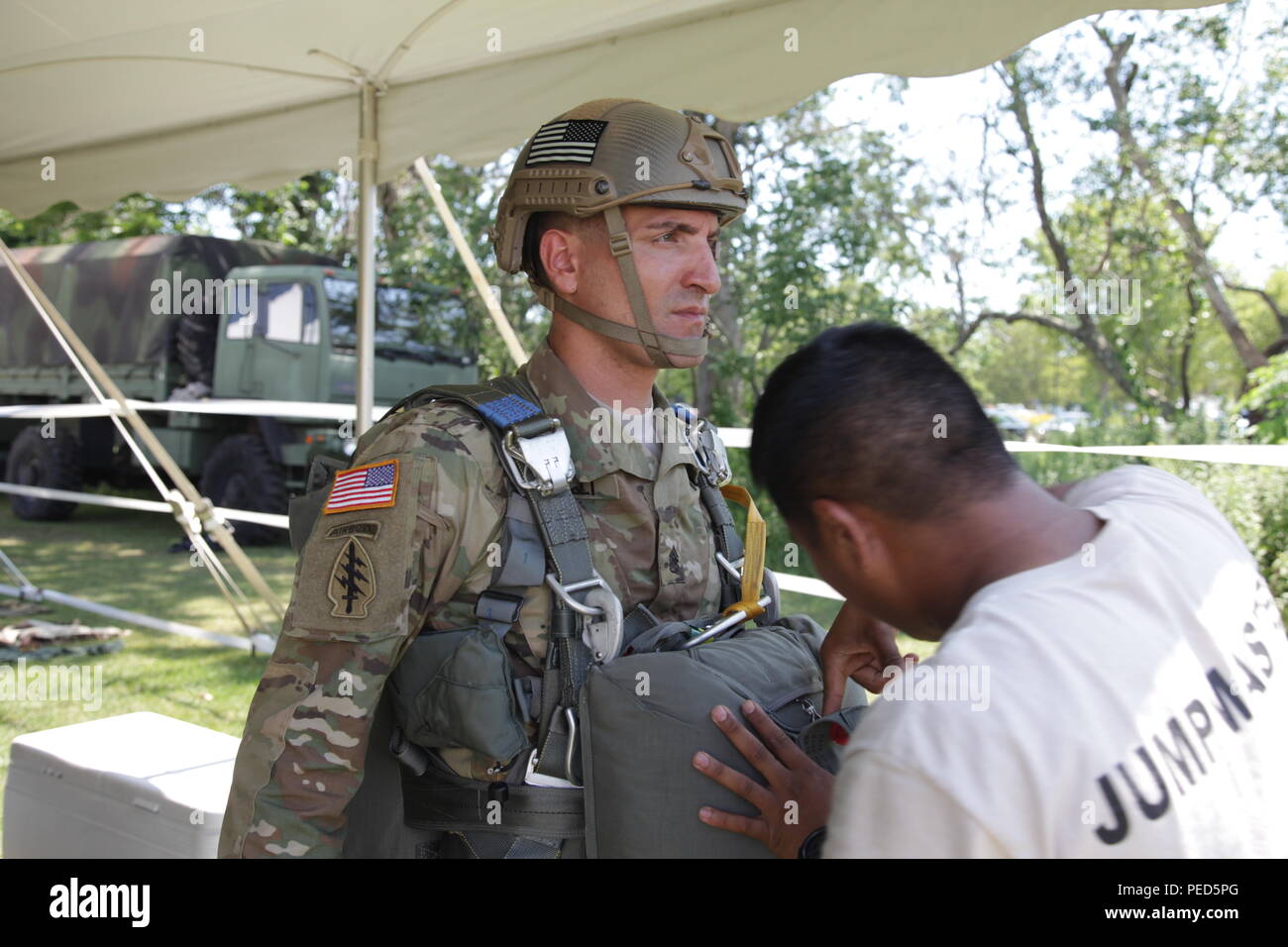 U.S. Army Staff Sgt. Justin Morelli, 982nd Combat Camera Co., waits as a rigger checks his parachute at Leapfest in West Kingston, R.I., Aug. 1, 2015. Leapfest is an International parachute competition hosted by the 56th Troop Command, Rhode Island National Guard to promote high level technical training and esprit de corps within the International Airborne community. (U.S. Army Photo by Spc. Josephine Carlson/Released) Stock Photo
