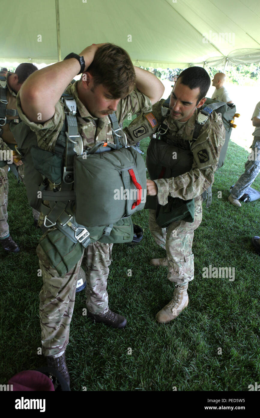 U.S. Army Sgt. Austin Berner, of the 982nd Combat Camera Company (Airborne), helps British Sgt. Owen Jones, of the 7th Parachute Regiment Royal Horse Artillery, rig up a MC-6 parachute during Leapfest 2015 in West Kingston, R.I., Aug. 1, 2015. Leapfest is an International parachute competition hosted by the 56th Troop Command, Rhode Island National Guard to promote high level technical training and esprit de corps within the International Airborne community. (U.S. Army Photo by Spc. Joseph Cathey/Released) Stock Photo