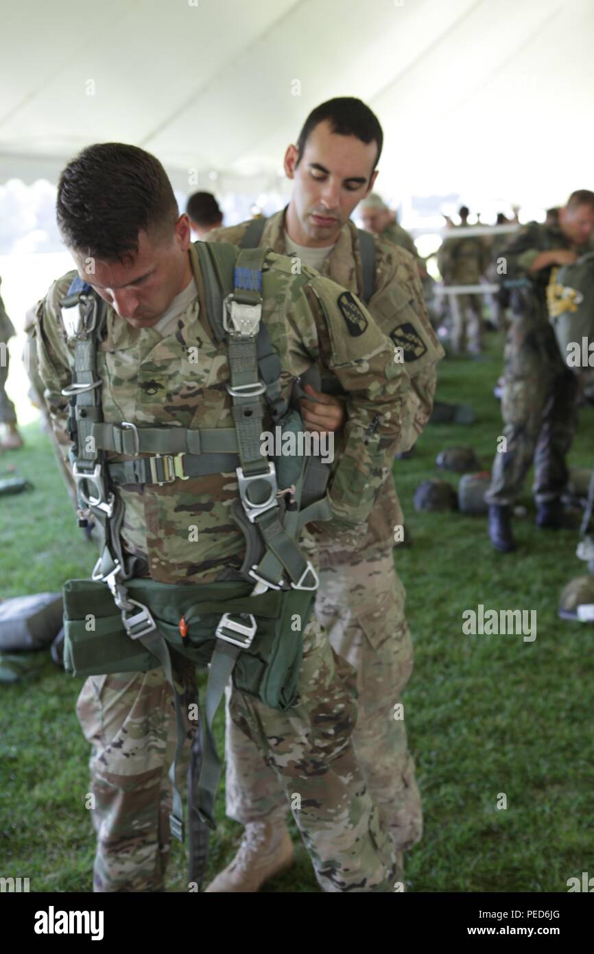 U.S. Army Staff Sgt. Justin Morelli and Sgt. Austin Berner, members of the 982nd Combat Camera Company (Airborne), work as a team rigging each other in their MC-6 parachutes for an international Wing exchange jump, Aug. 2, 2015. Leapfest is an International parachute competition hosted by the 56th Troop Command, Rhode Island National Guard to promote high level technical training and esprit de corps within the International Airborne community. (U.S. Army Photo by Sgt. 1st Class Horace Murray/Released) Stock Photo
