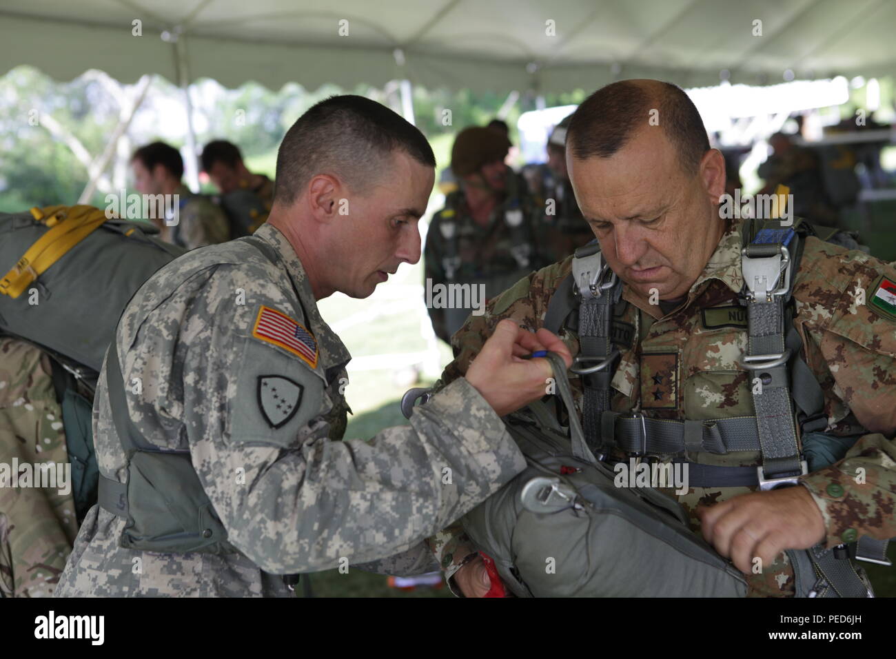 U.S. Army Staff Sgt. Paul Norwood from B Company, 1st Battalion, 143rd Infantry Regiment, Alaska National Guard, aids Italian 1st Lt. Antonio Nucera check the attachment of his reserve parachute for the wing exchange jump, Aug. 3, 2015.  Leapfest is an International parachute competition hosted by the 56th Troop Command, Rhode Island National Guard to promote high level technical training and esprit de corps within the International Airborne community. (U.S. Army Photo by Sgt. 1st Class Horace Murray/Released) Stock Photo