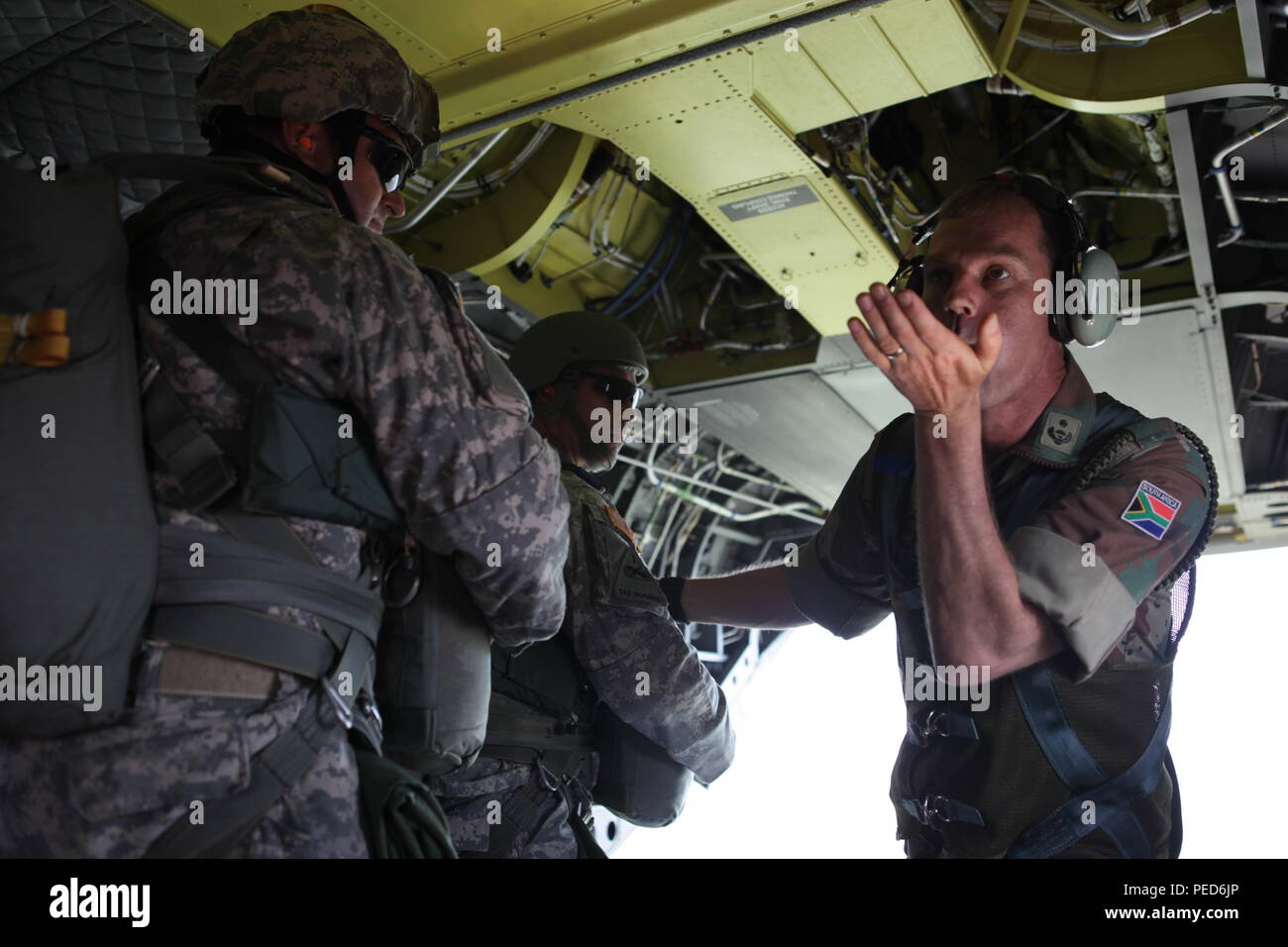 South African Lt. Col. Laurel Thatcher communicates to his paratroopers the wind speeds before sending them out of a U.S. Army CH-47 Chinook during the international wing exchange jump, Aug. 3, 2015.  Leapfest is an International parachute competition hosted by the 56th Troop Command, Rhode Island National Guard to promote high level technical training and esprit de corps within the International Airborne community. (U.S. Army Photo by Sgt. 1st Class Horace Murray/Released) Stock Photo
