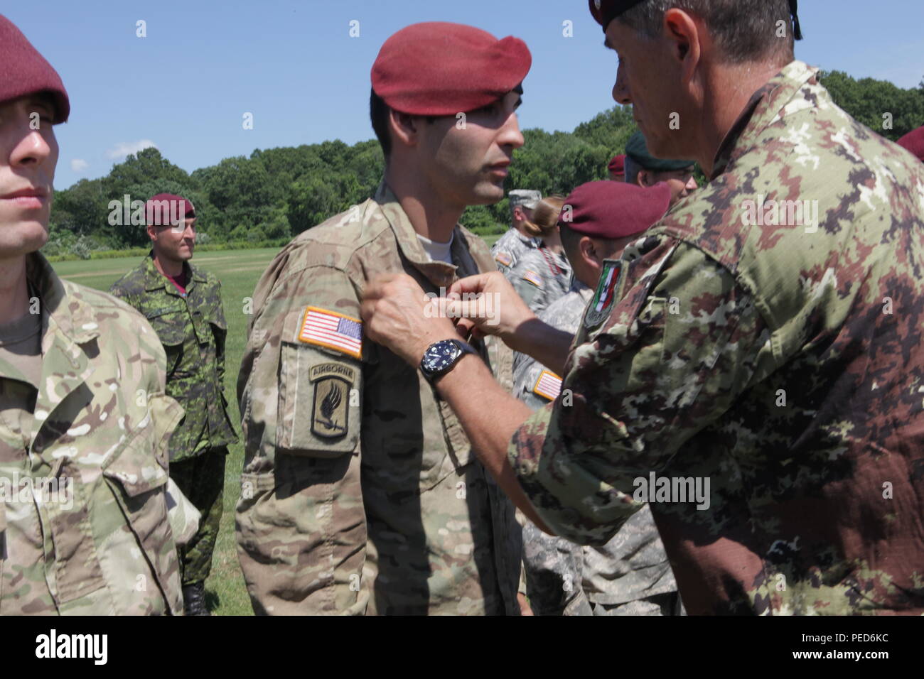 An Italian Jumpmaster pins Italian wings on U.S. Army Sgt. Austin Berner, from the 982nd Combat Camera Company (Airborne), during the wing exchange ceremony for completing a jump with an Italian jumpmaster, Aug. 3, 2015.  Leapfest is an International parachute competition hosted by the 56th Troop Command, Rhode Island National Guard to promote high level technical training and esprit de corps within the International Airborne community. (U.S. Army Photo by Sgt. 1st Class Horace Murray/Released) Stock Photo