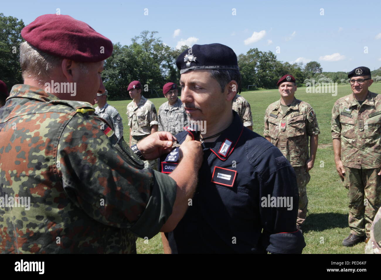 A German Jumpmaster pins German wings on an Italian Carabinieri paratrooper, during the wing exchange ceremony for completing a jump with a German jumpmaster, Aug. 3, 2015.  Leapfest is an International parachute competition hosted by the 56th Troop Command, Rhode Island National Guard to promote high level technical training and esprit de corps within the International Airborne community. (U.S. Army Photo by Sgt. 1st Class Horace Murray/Released) Stock Photo