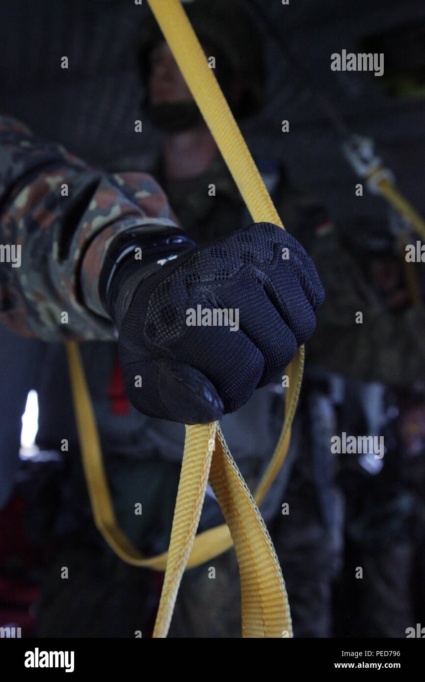 A German paratrooper uses a reverse bite on his universal static line to exit a CH-47 Chinook helicopter during the wing exchange jump at Leapfest in West Kingston, R.I., Aug. 3, 2015. Leapfest is an International parachute competition hosted by the 56th Troop Command, Rhode Island National Guard to promote high level technical training and esprit de corps within the International Airborne community. (U.S. Army Photo by Spc. Josephine Carlson/Released) Stock Photo