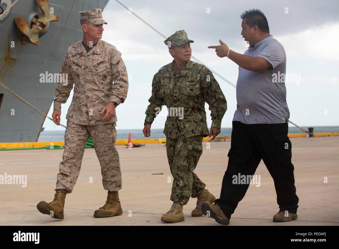 U.S. Marine Lt. Col. Eric Malinowski, the commanding officer of Combat Logistics Battalion 31, 31st Marine Expeditionary Unit, speaks with U.S. Navy Rear Adm. Bette Bolivar, the commander of U.S. Naval Forces Marianas, and Ralph Torres, the acting governor of Saipan, about typhoon relief efforts in Saipan, Aug. 9, 2015. The Marines and sailors of the 31st MEU and the ships of the Bonhomme Richard Amphibious Ready Group are assisting the Federal Emergency Management Agency with distributing emergency relief supplies to Saipan. Saipan, the most populated island in the Commonwealth of the Norther Stock Photo