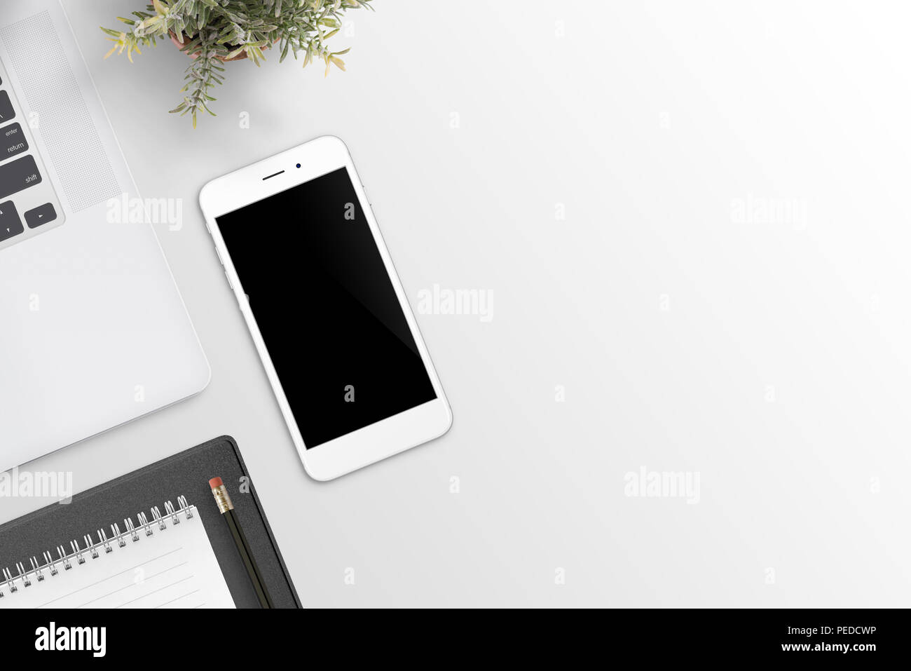 Phone mockup on office desk. Laptop computer, plant and pad beside. Flat lay. Top view. Stock Photo
