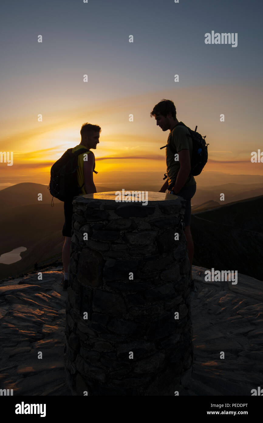Summit of Snowdon - two walkers enjoying the view at sunset. Stock Photo