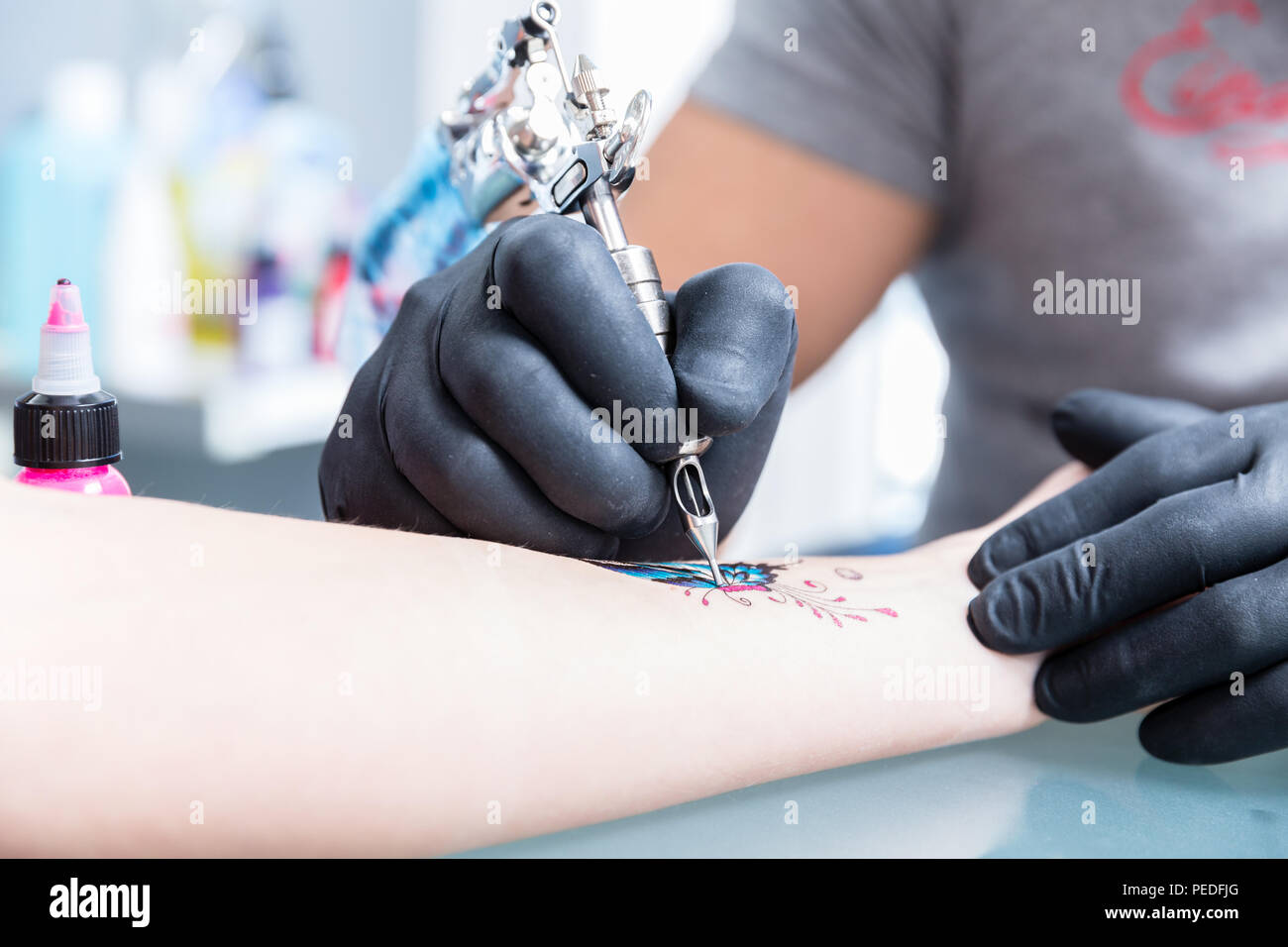Closeup of the hands of a skilled tattoo artist wearing black gloves