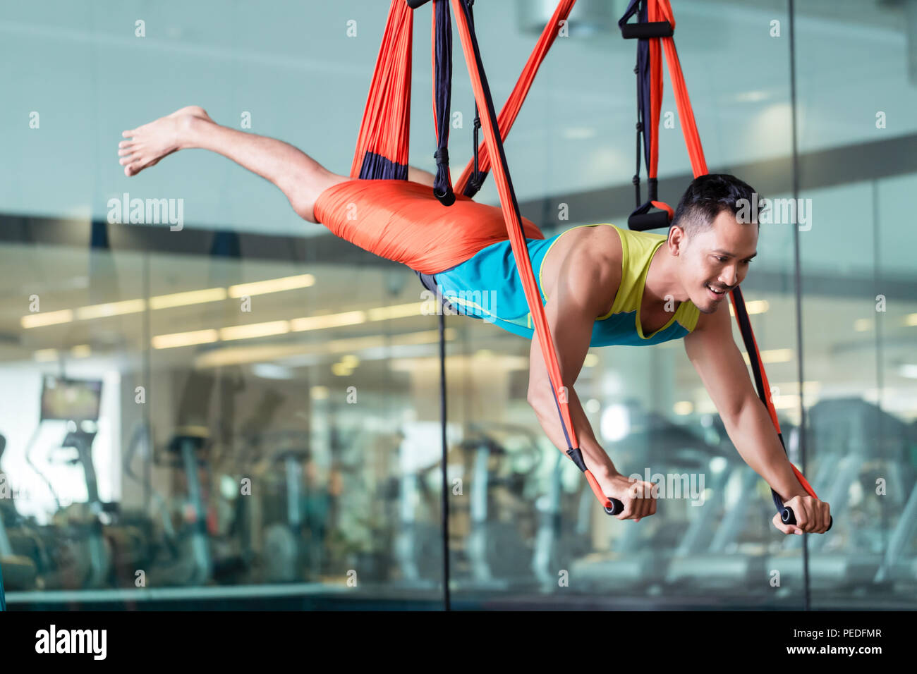 Fit handsome man smiling while practicing anti-gravity yoga Stock Photo