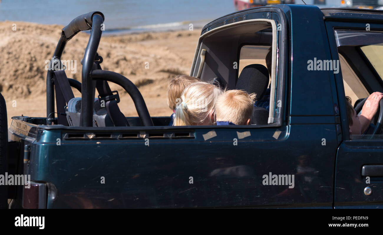 Kids in an open backseat of an offroad car during an annual event Stock Photo