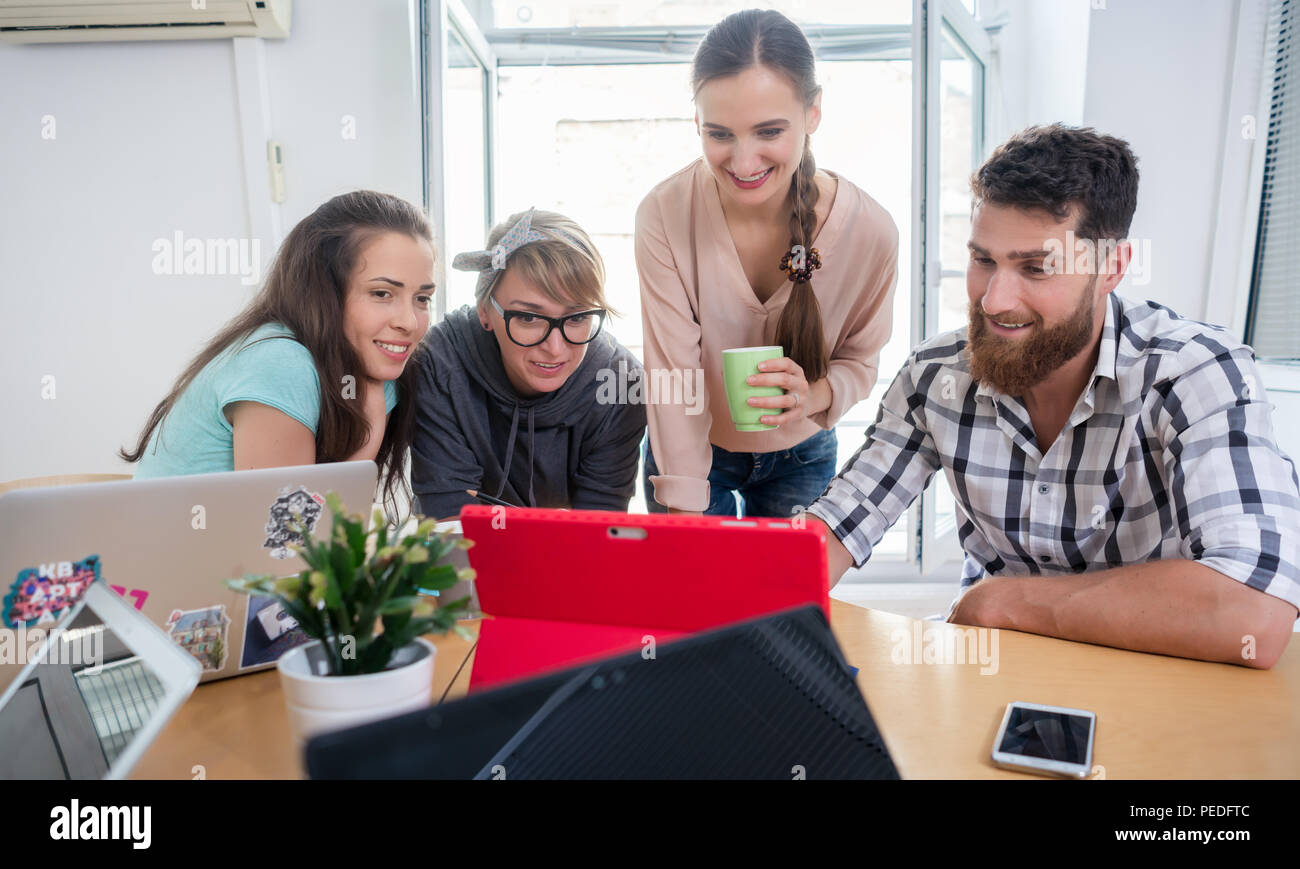 Four co-workers watching a business presentation in a modern shared office Stock Photo