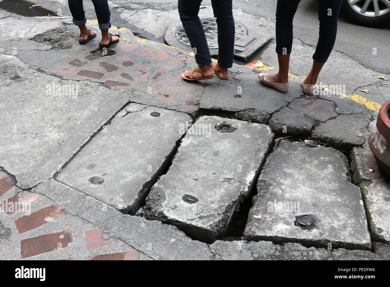 Dangerous city sidewalk in Manila, Philippines. Hazardous holes and