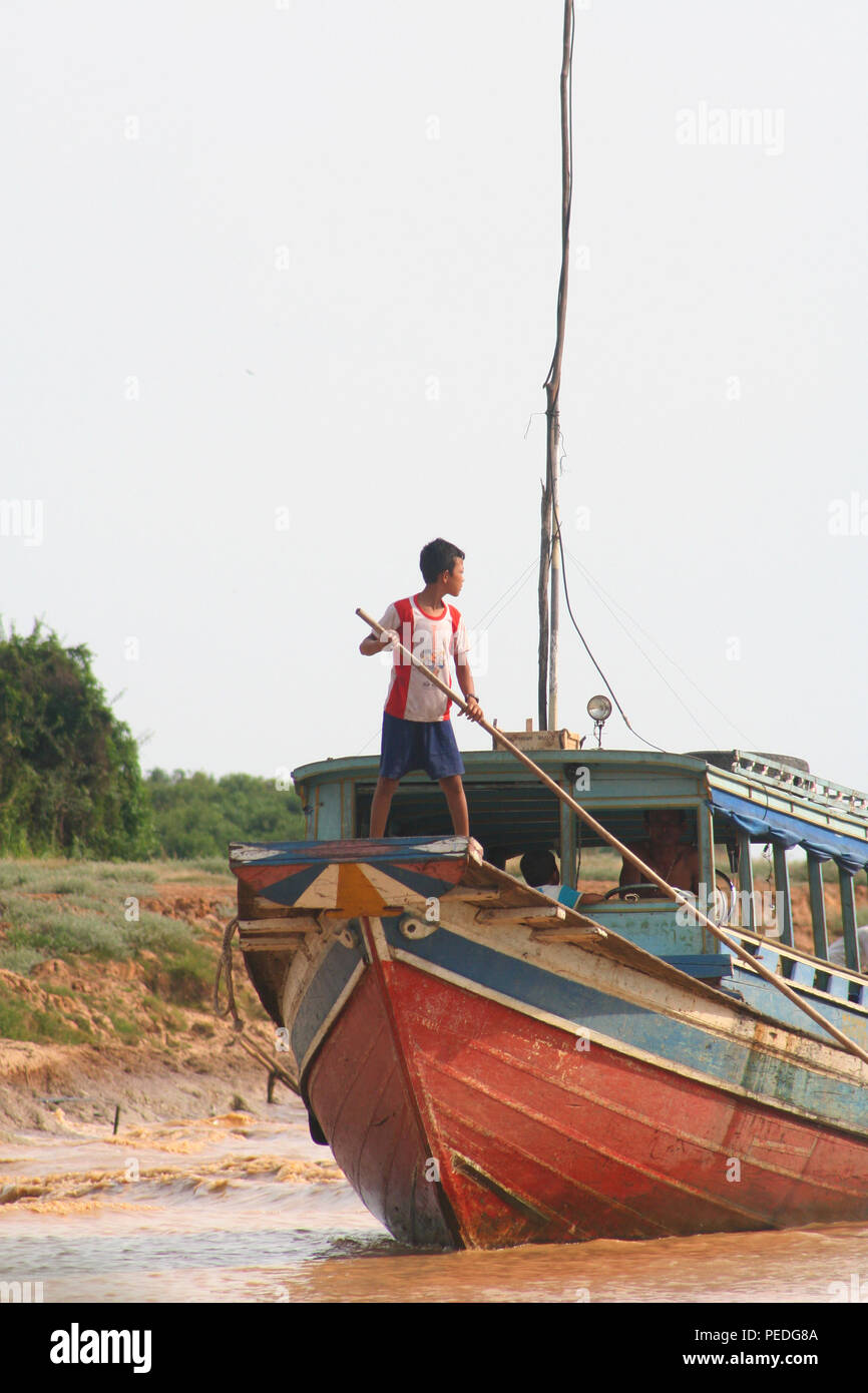 Boy crewing a local fishing boat, Tonle Sap Lake, Siem Reap, Cambodia Stock Photo