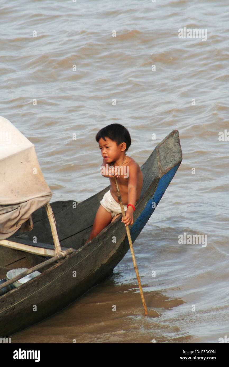 Young child steering a Boat on Tonle Sap Lake, Siem Reap, Cambodia Stock Photo