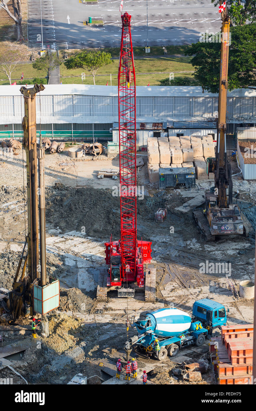 Vertical aerial view of an on-going construction industrial project at work site. Red cranes that pops out in the soiled area. Singapore Stock Photo