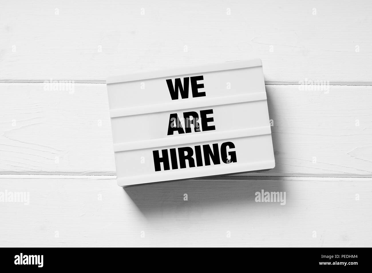 we are hiring text on light box sign on white wooden background, employment and recruitment concept Stock Photo
