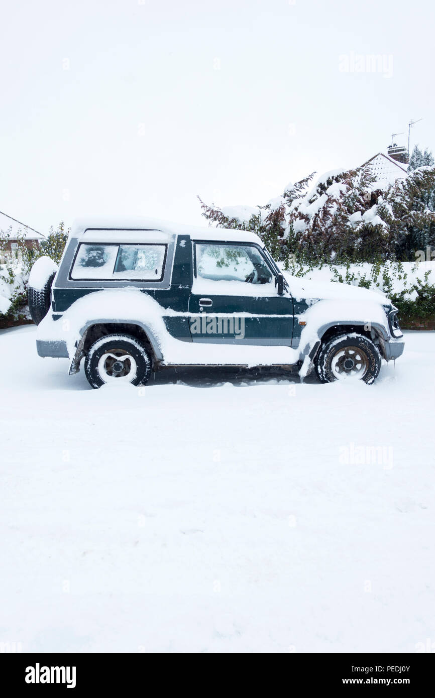 A snow covered 4x4 parked by the side of the road Stock Photo