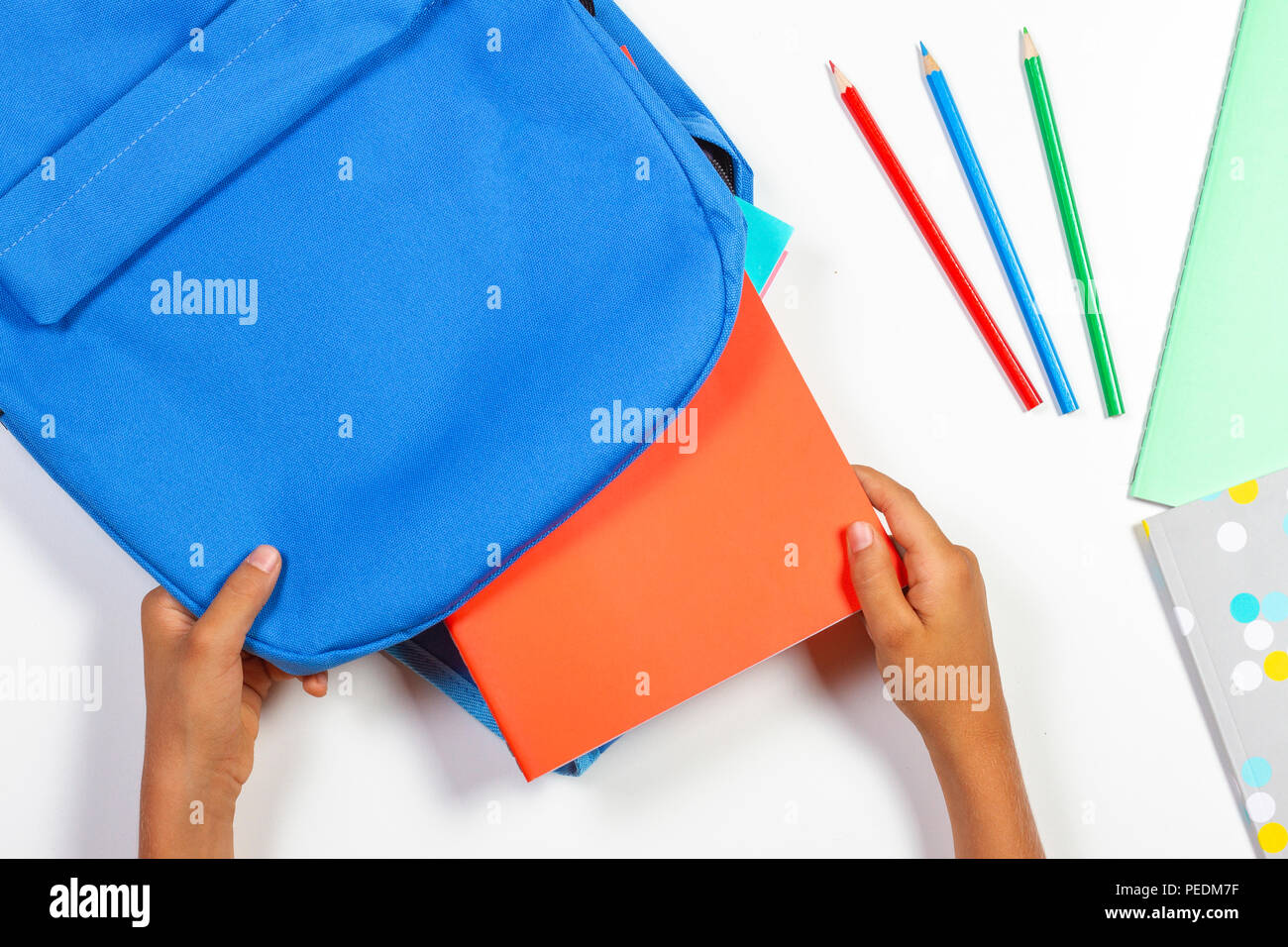 Back to school, education concept. Kid hands packing backpack and preparing for school. Top view Stock Photo