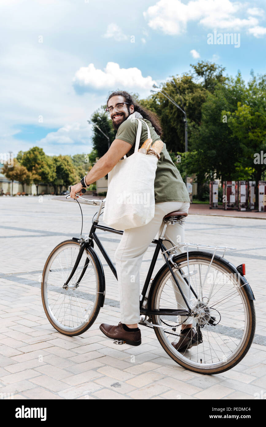 Pleasant happy man riding bike in the city Stock Photo