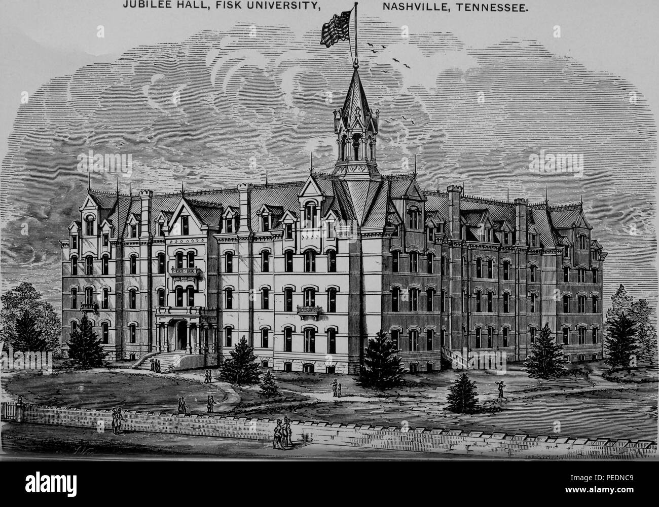 Black and white print of Fisk University's Jubilee Hall, a large Gothic Revival building, with a central tower surmounted by an American flag, and with pedestrians in Victorian dress in the foreground, located in Nashville Tennessee, 1880. Courtesy Internet Archive. () Stock Photo