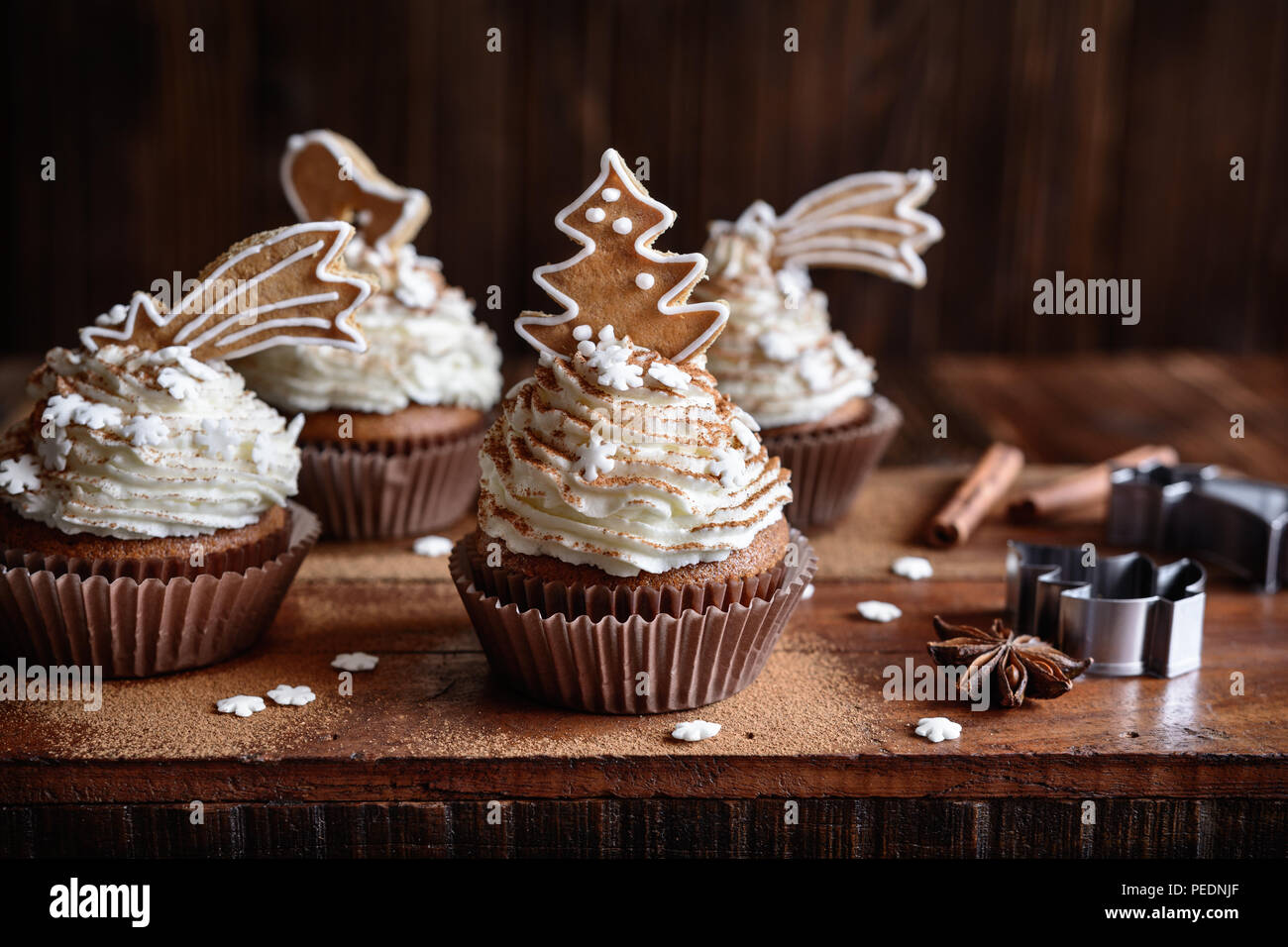 Homemade gingerbread cupcakes decorated with cinnamon and Christmas cookies and snowflake sprinkles Stock Photo