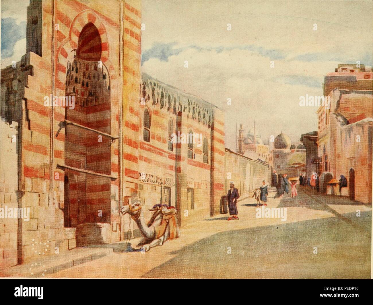 Color print depicting an early 20th-century street scene in the Sayeda Zainab quarter of old Cairo, Egypt, with a saddled camel seated in front of the high, arched entrance portal to a Mamluk style mosque, with its characteristic ablaq decorative technique layering light and dark blocks of stone, 1912. Courtesy Internet Archive. () Stock Photo