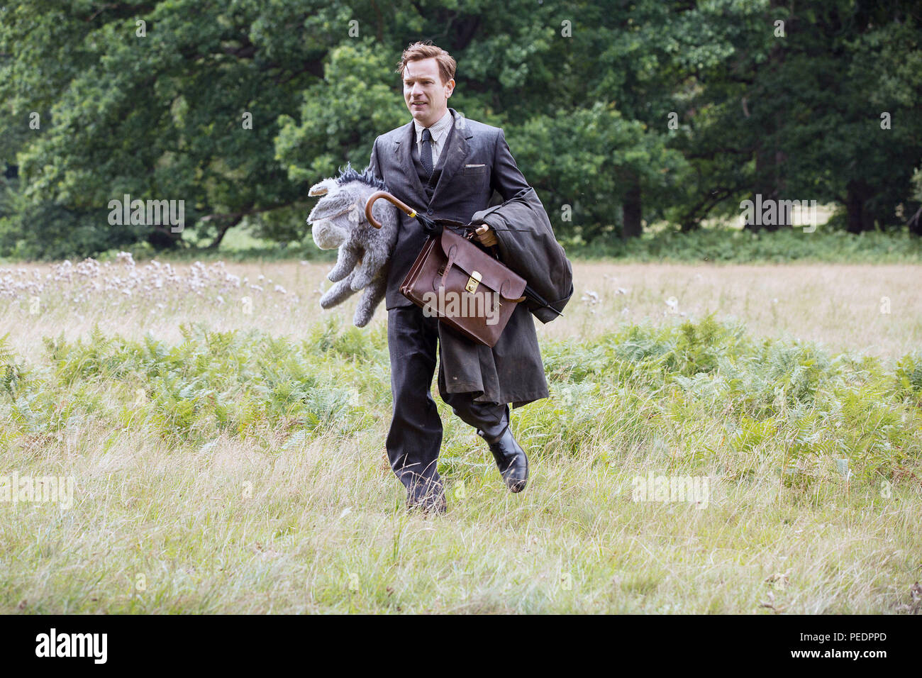 CHRISTOPHER ROBIN, Ewan McGregor as Christopher Robin carrying Eeyore