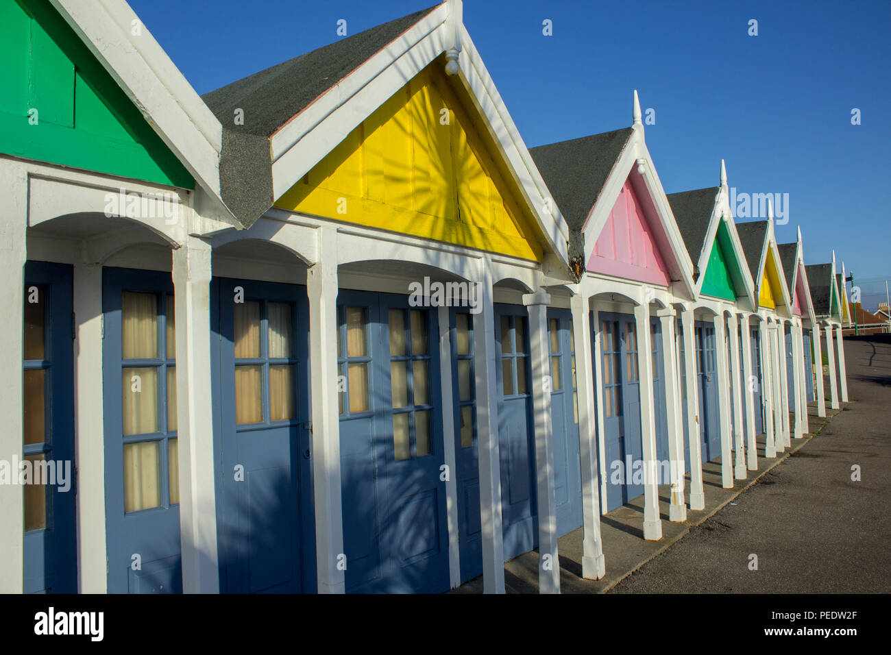 Closed up beach huts on a winter's day, with shadows of palm trees, Weymouth, Dorset, England Stock Photo