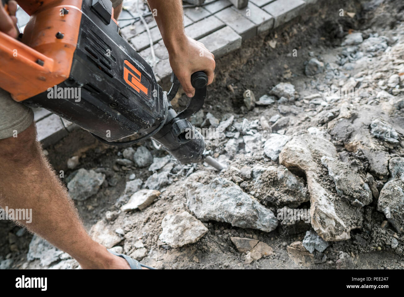 Workers use Electric Concrete Breaker. Male worker repairing driveway surface with jackhammer