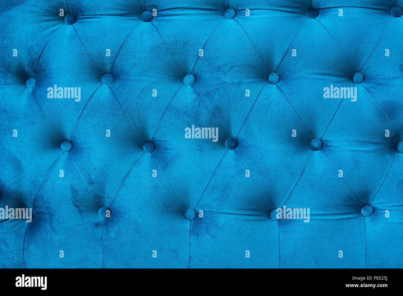 Velour surface of sofa close-up. Coach-type velours screed tightened with buttons. Blue chesterfield style quilted upholstery backdrop close up Stock Photo