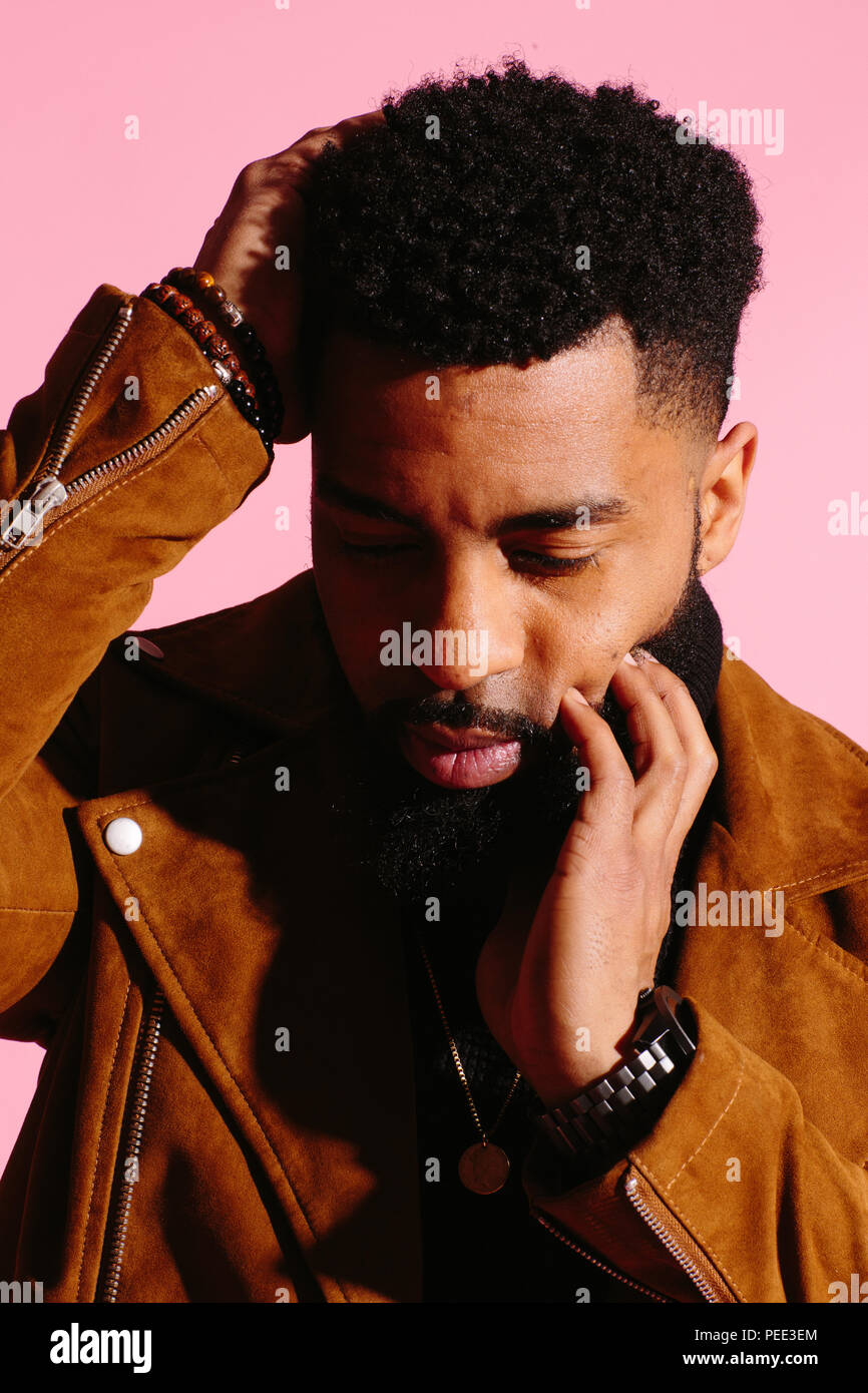 Stylish, handsome and cool African American man with beard, isolated on pink studio background Stock Photo